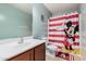 A bathroom with light blue walls, a Mickey Mouse themed shower curtain, and a wooden cabinet at 335 S Travis --, Mesa, AZ 85208