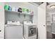 Bright laundry room showcasing a white front-load washer and dryer on a tile floor with overhead shelves at 335 S Travis --, Mesa, AZ 85208