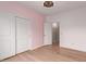 Comfortable bedroom with a pink wall, light wood floors, closet and white trim at 3440 W Mesquite St, Phoenix, AZ 85086