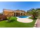 Inviting pool area with artificial turf, rock features, mature landscaping, and a covered patio at 346 E Red Mesa Trl, San Tan Valley, AZ 85143