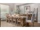 A dining room with a long wooden table, neutral chairs, and modern decor at 3483 E Bloomfield Pkwy, Gilbert, AZ 85296