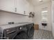 Well-equipped laundry room with tile floors, sink, washer, dryer, and ample cabinet space at 3483 E Bloomfield Pkwy, Gilbert, AZ 85296