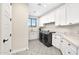 Bright laundry room featuring modern appliances, white cabinets, quartz countertops, patterned tile, and natural light at 35348 N 87Th St, Scottsdale, AZ 85266