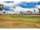 Scenic view of the lush golf course with palm trees, a pond, and players in the distance at 3690 N 150Th Ave, Goodyear, AZ 85395