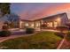 Inviting backyard with green lawn, desert landscaping, and a cozy seating area at dusk at 4614 W Fallen Leaf Ln, Glendale, AZ 85310