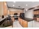 Open kitchen with black appliances, wood cabinets, and an island with bar seating at 4614 W Fallen Leaf Ln, Glendale, AZ 85310