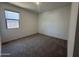 This bedroom features neutral paint, carpet flooring, and a sunlit window at 47251 W Mellen Ln, Maricopa, AZ 85139