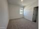 Neutral bedroom with plush carpet, bright white walls, a window, and a door to the hallway at 47251 W Mellen Ln, Maricopa, AZ 85139