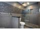 Modern bathroom with a pebble-stone shower, tiled walls and dark vanity with stone countertop at 4950 N Miller Rd # 122, Scottsdale, AZ 85251