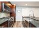 Bright kitchen showcasing stainless steel appliances, granite counters, gas cooktop and dark-stained wood cabinets at 4950 N Miller Rd # 122, Scottsdale, AZ 85251