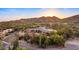 Stunning aerial view of a desert estate home with a swimming pool nestled against a mountain backdrop at sunset at 5480 E Desert Creek Ln, Cave Creek, AZ 85331