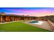 Lush backyard features an inviting swimming pool, an outdoor fireplace, and comfortable seating for relaxation at 5480 E Desert Creek Ln, Cave Creek, AZ 85331