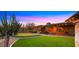Expansive backyard featuring a putting green, lush lawn, covered patio, and desert landscaping under a vivid twilight sky at 5480 E Desert Creek Ln, Cave Creek, AZ 85331