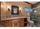 Warm-toned bathroom featuring a wood vanity, decorative mirror, tiled countertop, and glass-enclosed shower at 5480 E Desert Creek Ln, Cave Creek, AZ 85331