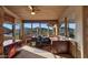 Comfortable office with brick pillars, wooden desk, ceiling fan, and mountain views from surrounding windows at 5480 E Desert Creek Ln, Cave Creek, AZ 85331