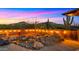Backyard water feature with natural rocks, desert landscaping, decorative lighting, and mountain views during sunset at 5480 E Desert Creek Ln, Cave Creek, AZ 85331