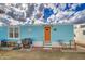 The exterior features a light blue mobile home with an orange door, outdoor seating, and tidy landscaping at 7807 E Main St # H12, Mesa, AZ 85207