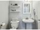 Clean and well-lit bathroom with a pedestal sink, toilet, and decorative shelves, creating a modern and functional space at 9264 E Hillery Way, Scottsdale, AZ 85260