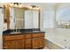 Bright bathroom featuring a double sink vanity with granite countertops, a soaking tub and a separate glass enclosed shower at 9264 E Hillery Way, Scottsdale, AZ 85260