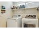 Modern laundry room with front-load washer and dryer, open shelving, and ample storage space at 9264 E Hillery Way, Scottsdale, AZ 85260