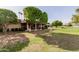 Backyard exterior featuring a lush green lawn, mature trees, shaded areas, and a serene outdoor setting at 9730 W Gulf Hills Dr, Sun City, AZ 85351