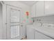 Bright laundry room with white washer and dryer, cabinetry, and exterior access to the side yard at 1005 W Berridge Ln, Phoenix, AZ 85013