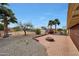 Spacious backyard featuring a brick patio, fire pit, palm trees and desert landscaping at 11067 W White Mountain Rd, Sun City, AZ 85351