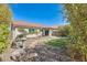 View of the home's back exterior, covered patio, and landscaped backyard featuring turf and rock features at 11229 E Emelita Ave, Mesa, AZ 85208