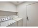 Well-lit laundry room with washer, dryer, shelving for extra storage, and door to access other areas at 11229 E Emelita Ave, Mesa, AZ 85208