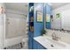 Charming bathroom with blue cabinets, tub-shower combo, decorative mirror and playful dinosaur art at 12132 W Daley Ln, Sun City, AZ 85373