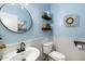 Powder room featuring a dark faucet, toilet and round mirror on the blue wall at 12132 W Daley Ln, Sun City, AZ 85373