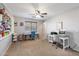 Bright bedroom with a ceiling fan, neutral walls, carpet floors, and craft station setup at 12132 W Daley Ln, Sun City, AZ 85373