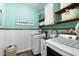 Well-organized laundry room featuring modern washer and dryer, sink, and wood shelving, with blue-green walls and white accents at 12132 W Daley Ln, Sun City, AZ 85373