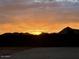 Backyard block fence view with colorful sunset and a distant mountain view at 12204 W Black Hawk Rd, Casa Grande, AZ 85194