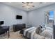 This light blue bedroom features a ceiling fan, TV, desk, and a window providing natural light at 12204 W Black Hawk Rd, Casa Grande, AZ 85194