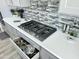 Close-up of a modern kitchen with stainless steel gas cooktop and pot filler, and gray cabinets at 12204 W Blackhawk Rd, Casa Grande, AZ 85194