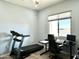 Home office with a treadmill, sleek black desk setup, and bright natural light from the window at 12204 W Black Hawk Rd, Casa Grande, AZ 85194