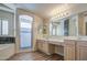 Well-lit bathroom with double vanity, soaking tub, and glass-enclosed shower, offering relaxation and convenience at 13236 N 13Th St, Phoenix, AZ 85022