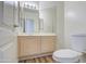 Well-lit bathroom with wooden cabinets, large mirrors, and a modern toilet, creating a clean and functional space at 13236 N 13Th St, Phoenix, AZ 85022