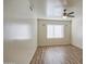 This empty room has neutral paint, wood floors, a ceiling fan, and bright window that makes this space inviting at 13236 N 13Th St, Phoenix, AZ 85022