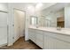 Bathroom with dual sinks, white cabinets, framed mirror, and tiled floors at 17165 W Corrine Dr, Surprise, AZ 85388