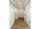 Long hallway with neutral walls, tray ceiling, wood floors, and an entry door at 17165 W Corrine Dr, Surprise, AZ 85388