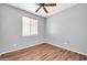 A freshly painted bedroom features modern wood flooring, a ceiling fan, and a window at 18033 W Carmen Dr, Surprise, AZ 85388