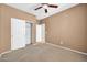 Neutral bedroom featuring carpet, ceiling fan, and closet with sliding doors at 18033 W Carmen Dr, Surprise, AZ 85388