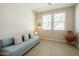 Bright living room features tile floors, light blue sofa with throw pillows, and a small table between two large windows at 1804 E Amaranth Trl, Queen Creek, AZ 85140