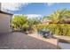 Seating area on a paved patio with outdoor dining table and chairs surrounded by lush landscaping and sunny sky at 1804 E Amaranth Trl, Queen Creek, AZ 85140