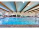 Well-lit indoor swimming pool featuring multiple lanes, tiled flooring, and large glass windows for natural light at 19765 N Swan Ct, Maricopa, AZ 85138