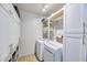 Well-lit laundry room with white cabinets, shelving, and a modern washing machine and dryer at 2002 E Mitchell Dr, Phoenix, AZ 85016