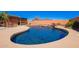 Inviting backyard swimming pool with a rock waterfall feature and mature plants at 22005 N 86Th Ave, Peoria, AZ 85383