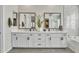 Modern bathroom with dual vanity, white cabinets, gray tile floor, and stylish mirrors at 2205 E Fallen Leaf Ln, Phoenix, AZ 85024